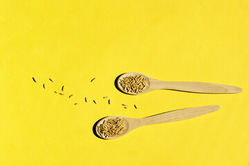 Cereal crop on a Illuminating Yellow background. Wooden spoons with hard shadows. Natural raw materials for food. Demonstrating trendy Color of the Year 2021. 