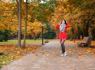 Fototapeta premium young girl in a red coat standing on the alley