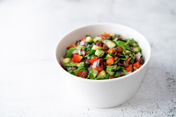 Green lentil red bell pepper cucumber parsley salad in a bowl