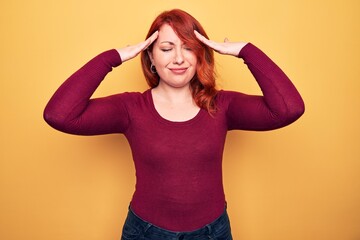 Young beautiful redhead woman wearing casual sweater standing over yellow background with hand on head, headache because stress. Suffering migraine.