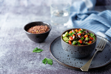 Green lentil red bell pepper cucumber parsley salad in a bowl