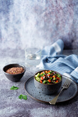 Green lentil red bell pepper cucumber parsley salad in a bowl