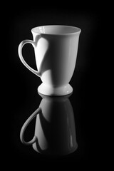 Black and white photo, white coffee cup isolated on black background. The light and shadow pattern on the side of the pen forms an image of a heart