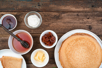 Pancakes and various additives to pancakes on a brown wooden background. Top view, horizontal orientation. The concept of cooking, Mardi Gras.