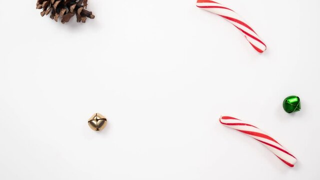 Beautiful holiday background loop of pine cones, candy cane sticks, and green, gold and silver jingle bells quickly adding and taking away one at a time.