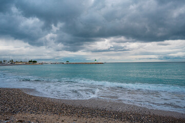 Fototapeta premium Lighthouse on the beautiful azure sea under the cloudy sky. Panoramic sea view