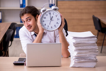 Young male employee in time management concept in the office