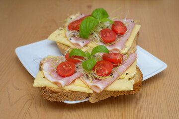 Fototapeta na wymiar smaczne domowe tosty z serem, szynką i pomidorami oraz kiełki