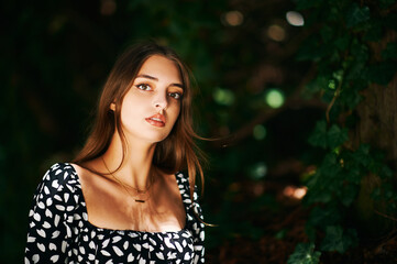 Fashion portrait of young woman posing in beautiful forest, wearing black and white dress