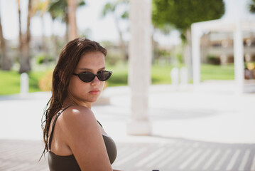 Fashion cute young teenage girl or woman posing in summer swimsuit with a lifebuoy. Trendy girl posing. Funny and positive woman in sunglasses