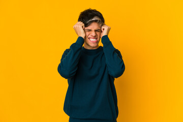 Young skinny hispanic man covering ears with hands.