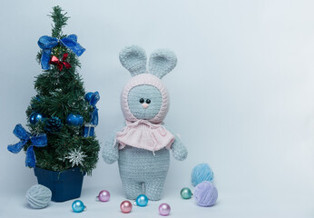 Knitted plush bunny near the Christmas tree