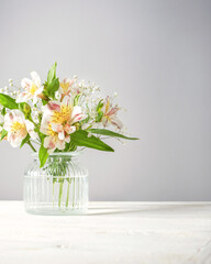Fresh delicate white flowers freesia with funny glass vases in green mint menthe interior on white wood board, copy space.