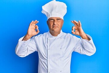 Mature middle east man wearing professional cook uniform and hat relax and smiling with eyes closed doing meditation gesture with fingers. yoga concept.