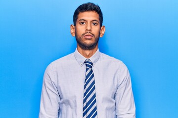 Young latin man wearing business clothes with serious expression on face. simple and natural looking at the camera.