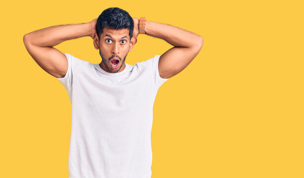 Young latin man wearing casual clothes crazy and scared with hands on head, afraid and surprised of shock with open mouth