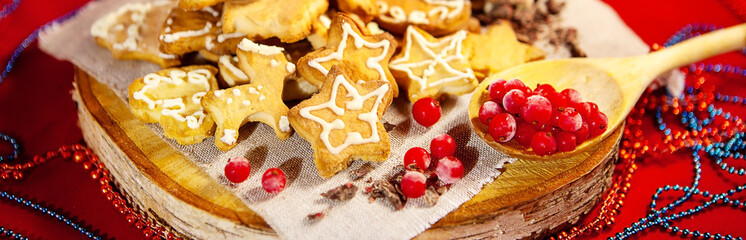 Christmas gingerbread cookies, chocolate and frozen berries, on a wooden stand, red background. Christmas and New Year concept.