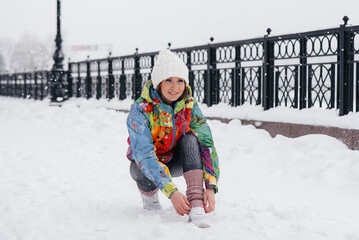 Fototapeta na wymiar A young athletic girl ties her shoes on a frosty and snowy day. Fitness, running