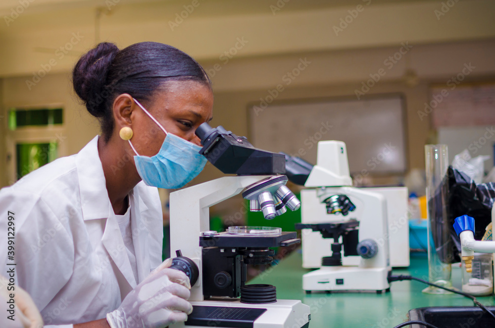 Wall mural young african scientist looking through a microscope in the laboratory about the vaccine she is work