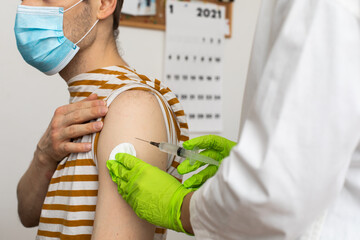 Man receives jab, male getting vaccinated. Pacents gets a shot Doctors set to give first authorised doses of Covid-19 vaccine. There are currently more than 50 COVID-19 vaccine candidates in trials - obrazy, fototapety, plakaty