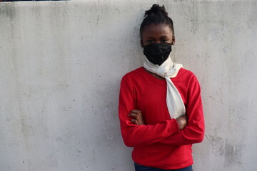 Obraz premium Black Girl wearing mask red sweater and winter scarf arms crossed outdoors white wall background 