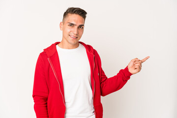 Young caucasian handsome man isolated smiling cheerfully pointing with forefinger away.