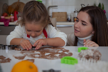 Obraz na płótnie Canvas Caucasian mother and daughter cooking ginger bread in the kitchen. Christmas cooking concept. Mother and daughter cooking concept. 