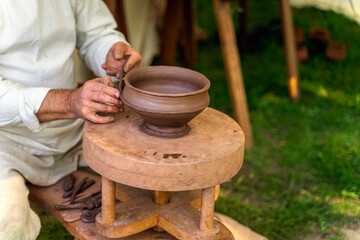 Fototapeta na wymiar Craftsman hand making pottery from clay on potters wheel at historical reenactment of Slavic or Vikings lifestyle around 11th century, Cedynia, Poland