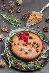 Raisin pie on black plate among rosemary and cranberries. Slice of pie on cake shovel. View from above