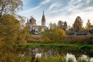 Fototapeta na wymiar Golden autumn. An old rural church that needs restoration. In the foreground is a small body of water.