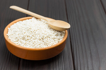 White rice in ceramic bowl and wooden spoon on top
