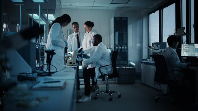Medical Science Laboratory with Diverse Multi-Ethnic Team of Microbiology Scientists Have Meeting on Developing Drugs, Medicine, Doing Biotechnology Research. Working on Computers, Analyzing Samples