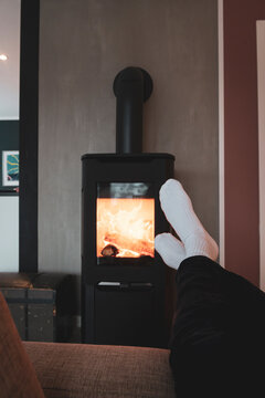 Person Relaxing By The Fireplace, Warming Feet By The Fire, On The Couch By A Modern Fireplace