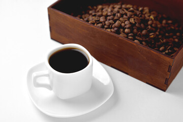 white cup of coffee on a white saucer, natural wooden box with coffee beans on a white background, isolate, angle view from above top
