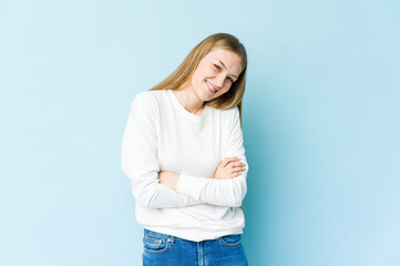 Young blonde woman isolated on blue background laughing and having fun.