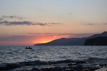 Fototapeta premium people on a boat at sea sunset