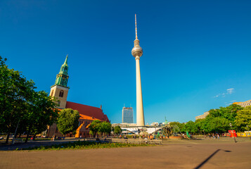 Obraz premium The Berliner Fernsehturm (Berlin TV Tower) and St. Marienkirche (St. Mary's Church) in Berlin Mitte on a May day.