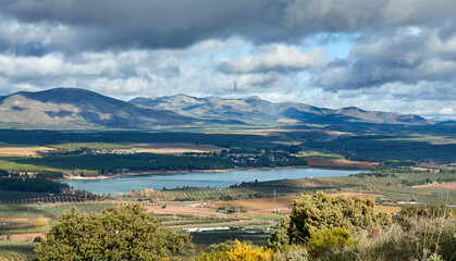 Panoramic view of the Cubillas reservoir between fields and mountains on a cloudy autumn day