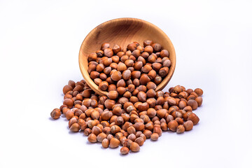 Hazelnuts spilled from wooden bowl on white background. Solid ripe Hazelnuts