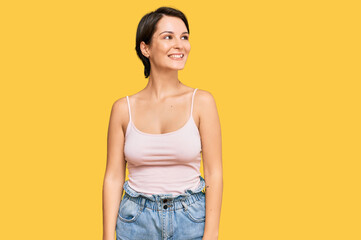 Young brunette woman with short hair wearing casual summer clothes looking away to side with smile on face, natural expression. laughing confident.