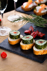 Christmas tapas with spinach rolls and dried tomatoes. New year celebration with white wine, toasts for party dinner