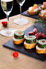 Christmas tapas with spinach rolls and dried tomatoes. New year celebration with white wine, toasts for party dinner