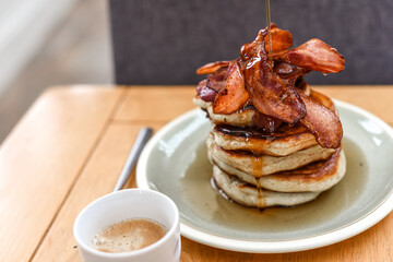 Pancake stack with golden syrup and a large portion of bacon as a breakfast or brunch meal