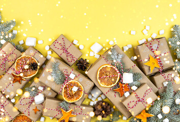 Many craft gift boxes and garland bokeh lights on yellow background. Christmas new year zero waste still life