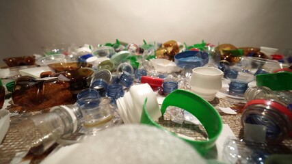 Plastic bottles parts, cups, corks, straws, water and shampoo bottles, creams packaging and other one-time use garbage dumped on the table. Environmental pollution, recycle, waste management problem.