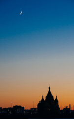 Fototapeta premium silhouette of the church on the background of sunset, in the sky a crescent