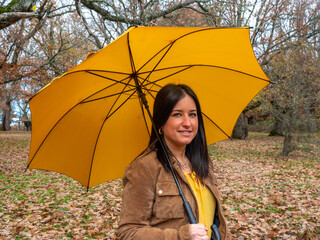 Pretty young woman with a yellow umbrella in an oak forest in winter.