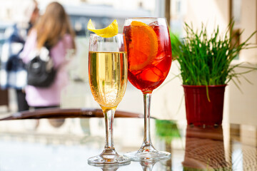 Two glasses of sparkling wine cocktails and Aperol Spritz cocktails on table in terrace of restaurant or summer cafe