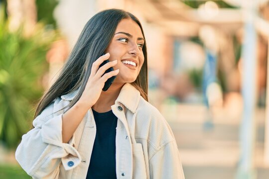Young hispanic girl smiling happy talking on the smartphone at the park.