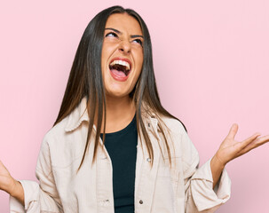 Beautiful hispanic woman wearing casual clothes crazy and mad shouting and yelling with aggressive expression and arms raised. frustration concept.